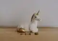 white and gold ceramic unicorn figurine near coins